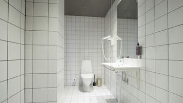 Een moderne badkamer met witte betegelde wanden, een toilet, een wastafel en een douchehoek.