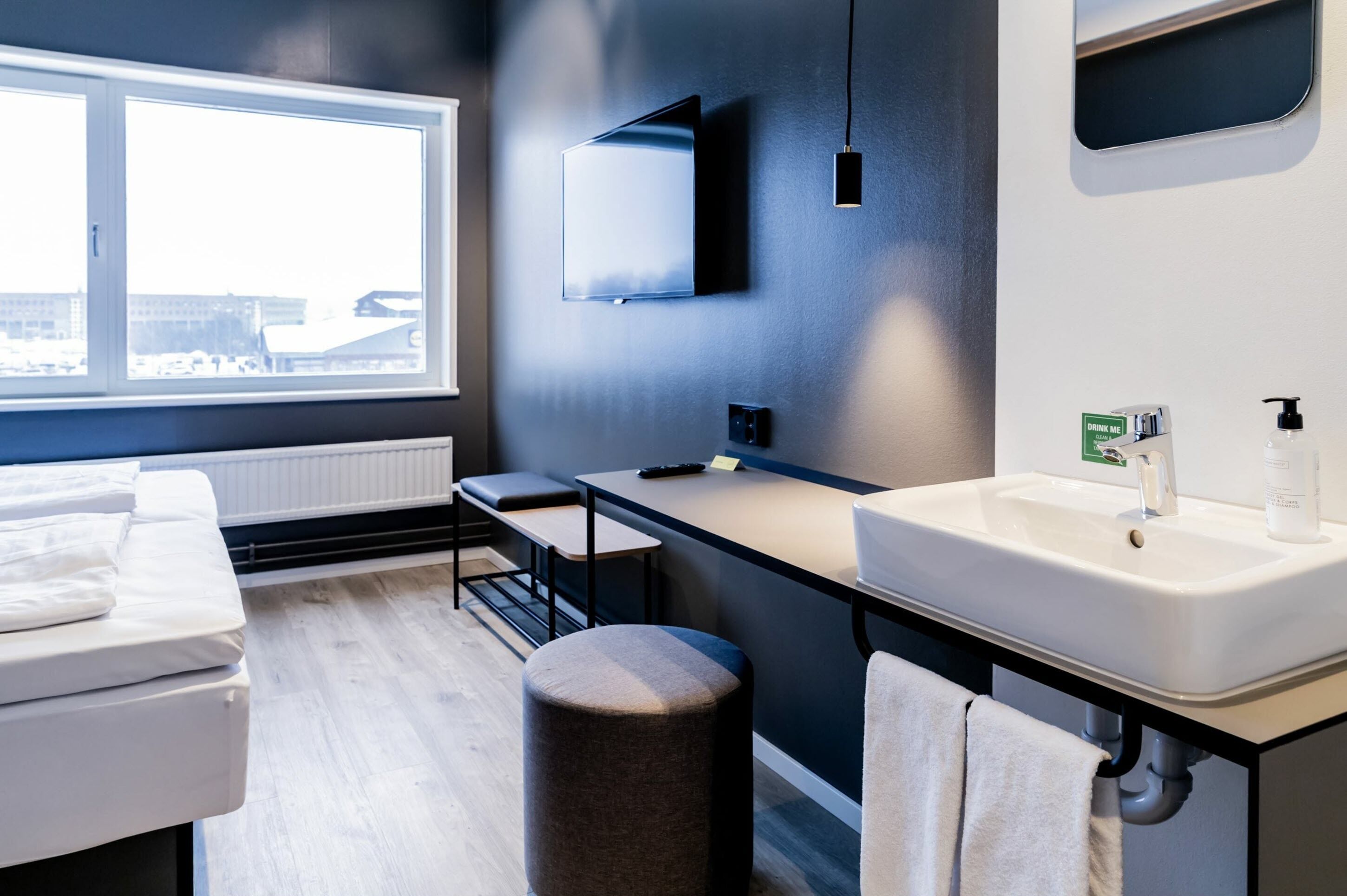 A modern bathroom with a large window, a sink, a mirror, and a bench.