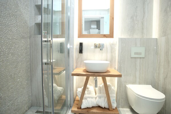 Une salle de bain moderne avec une douche à parois de verre, un meuble-lavabo en bois avec un lavabo blanc et des toilettes blanches.