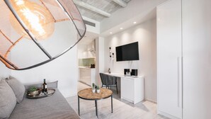 A modern living room with a sofa, a round wooden table, and a hanging light fixture.