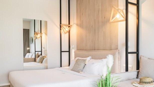A modern bedroom with a large bed, a round wooden table, and a mirror.