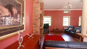 A living room with a fireplace, a large framed painting, and a red carpet. - Auchenheglish Lodges - The Coachhouse (Alexandria)