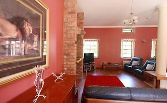Una sala de estar con chimenea, un cuadro grande enmarco y una alfombra roja.