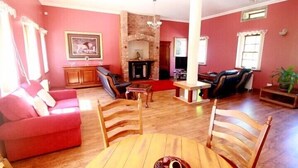 A living room with a fireplace, a sofa, a dining table, and a TV. - Auchenheglish Lodges - The Coachhouse (Alexandria)
