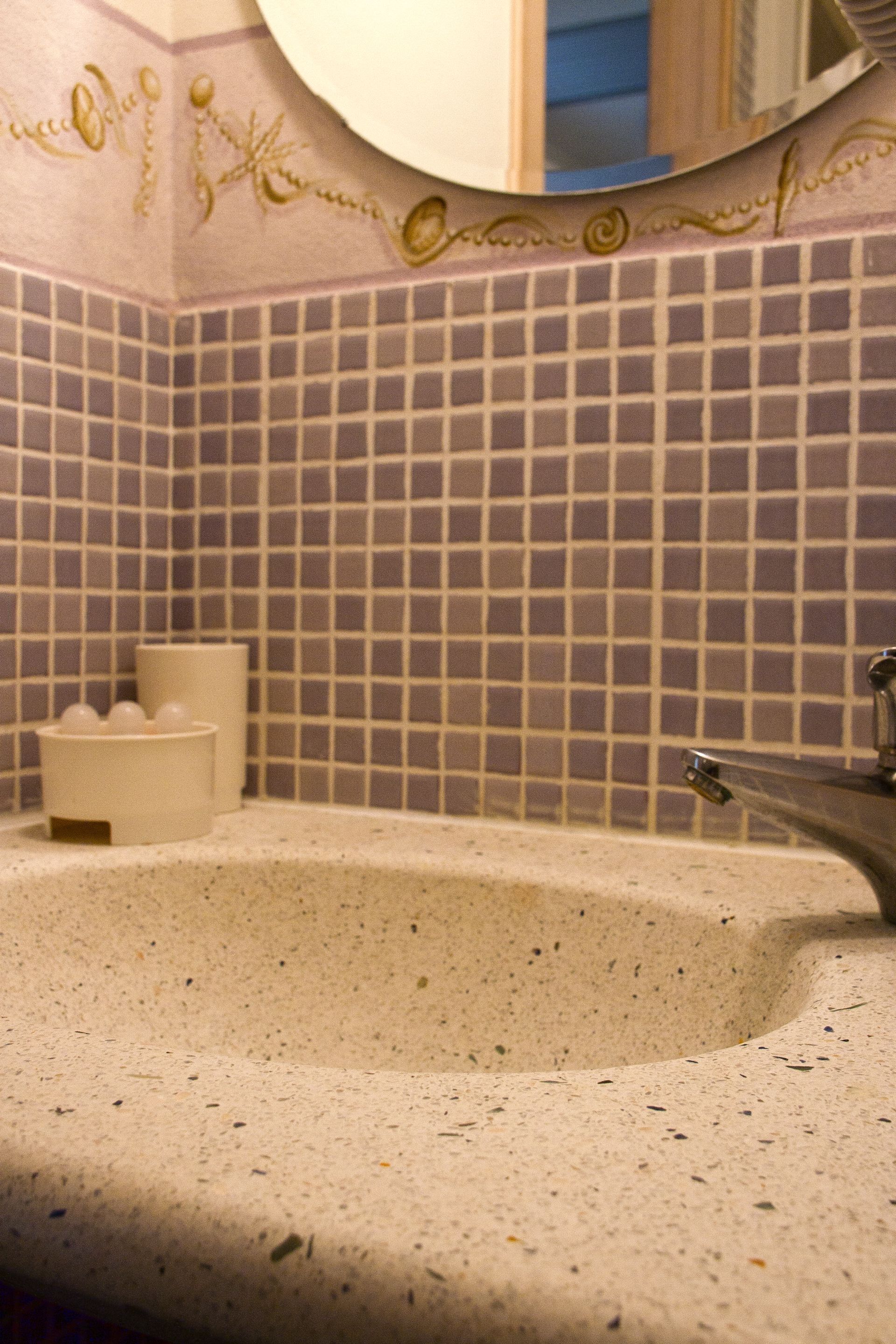 Un lavabo de baño con espejo, paredes de azulejos y un pequeño jabonera.