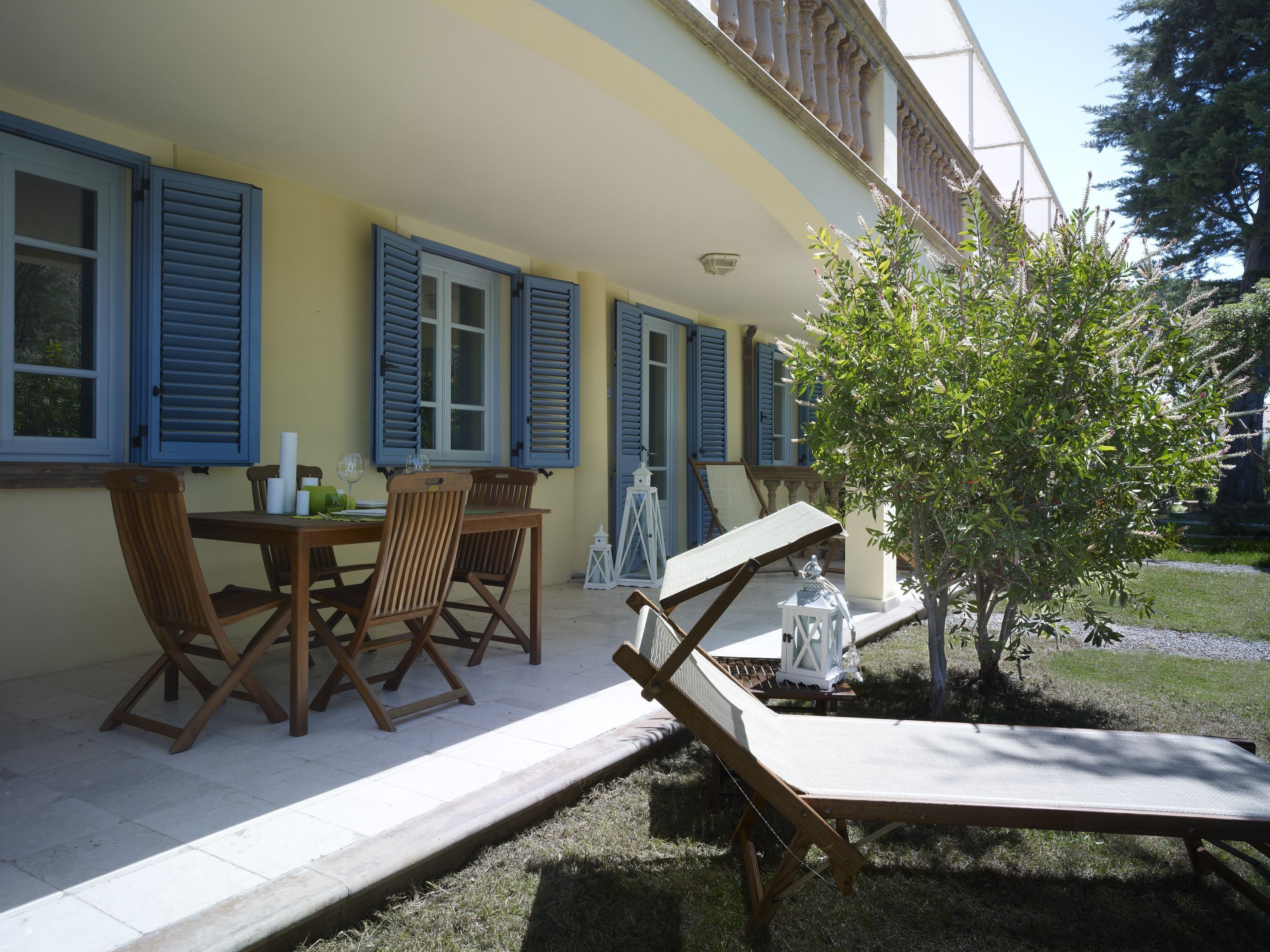 Un espace patio aménagé avec une table et des chaises, un petit arbre et une lanterne blanche.