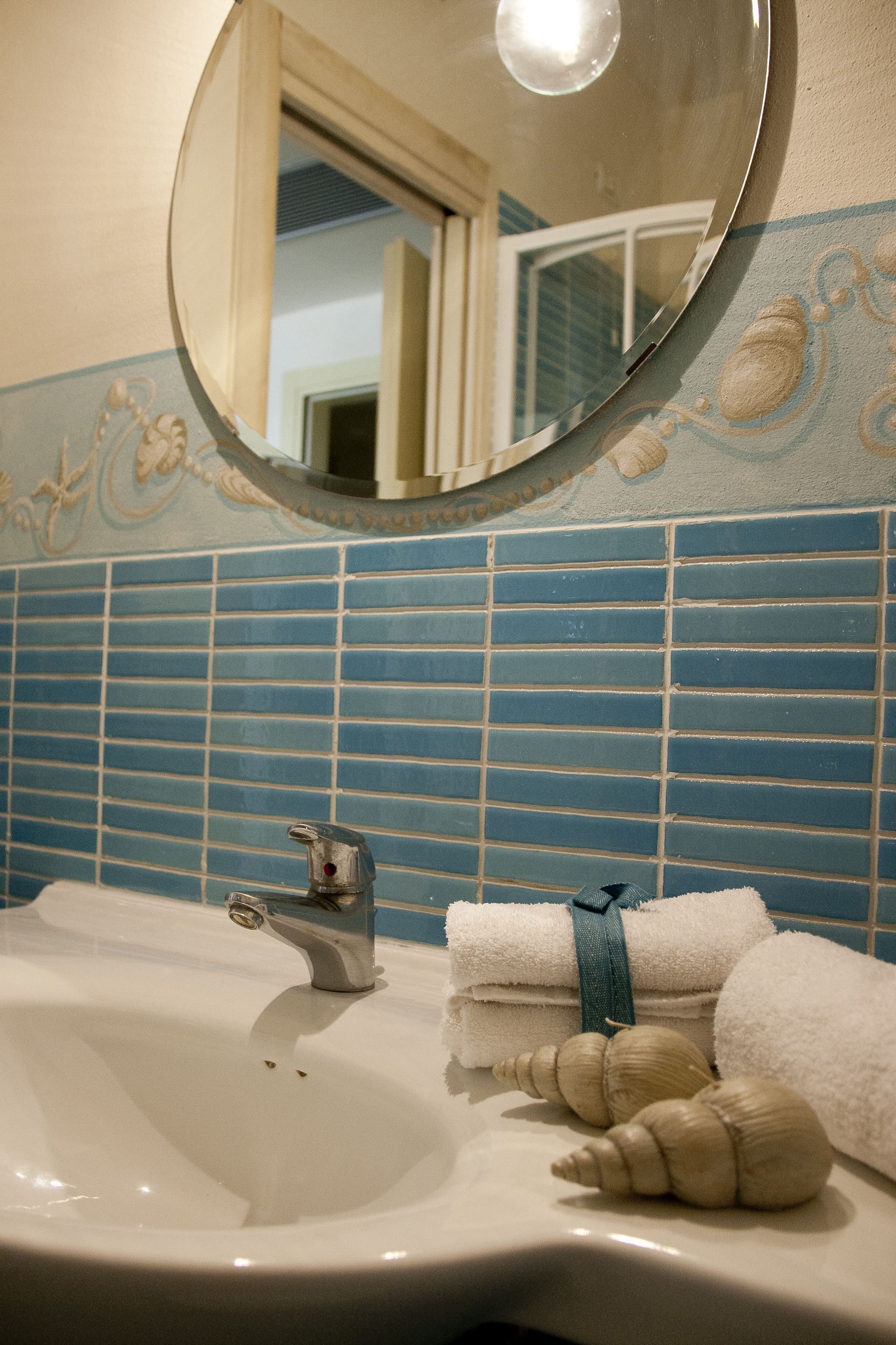 Un baño con lavamanos, espejo y azulejos decorativos.