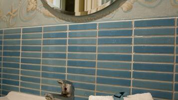 Un baño con lavamanos, espejo y azulejos decorativos.
