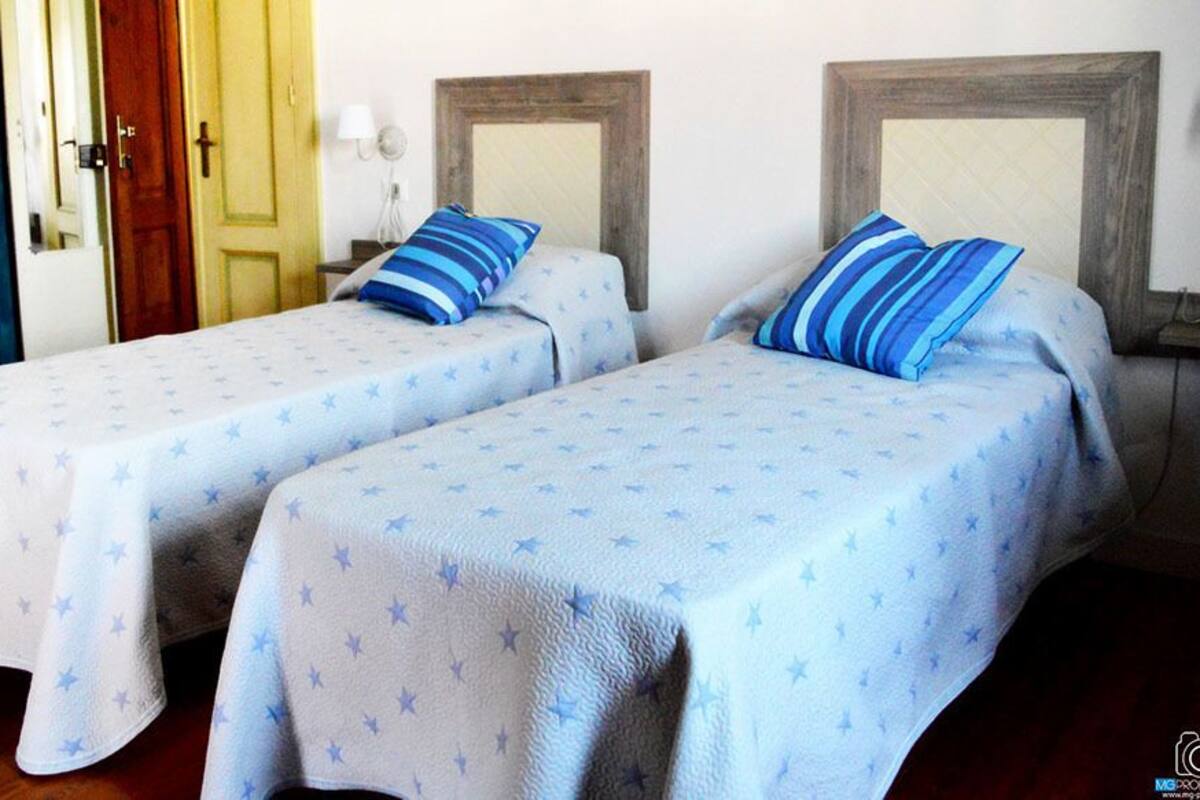 Two twin beds with star-patterned bedding, wooden headboards, and a wooden floor.