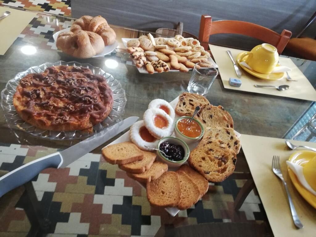 A table with various food items including bread, pastries, and a pizza.