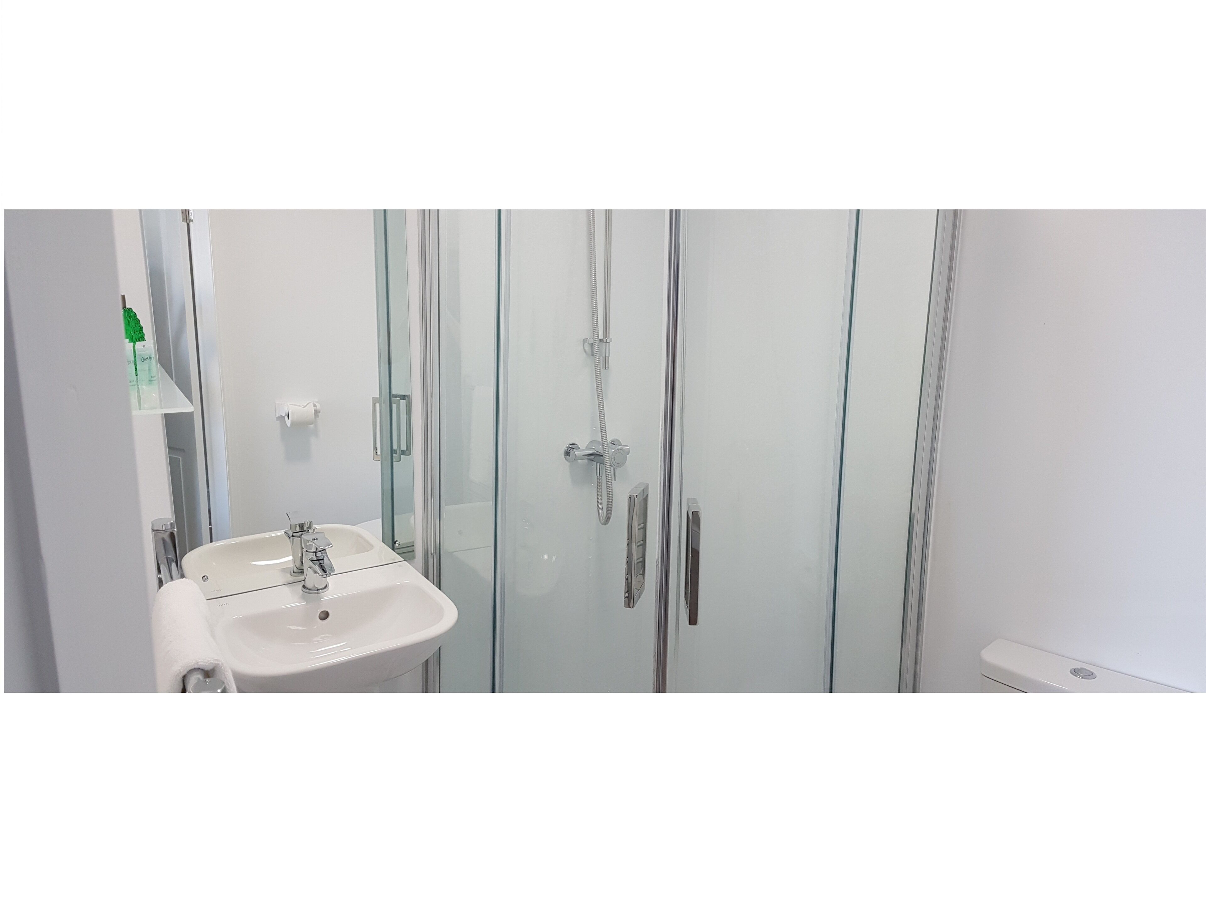 A bathroom with a glass-enclosed shower, a white sink, and a mirror.