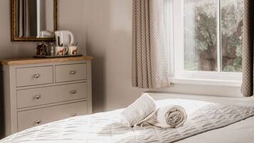 A bedroom with a bed, a dresser, a mirror, and a window with curtains.