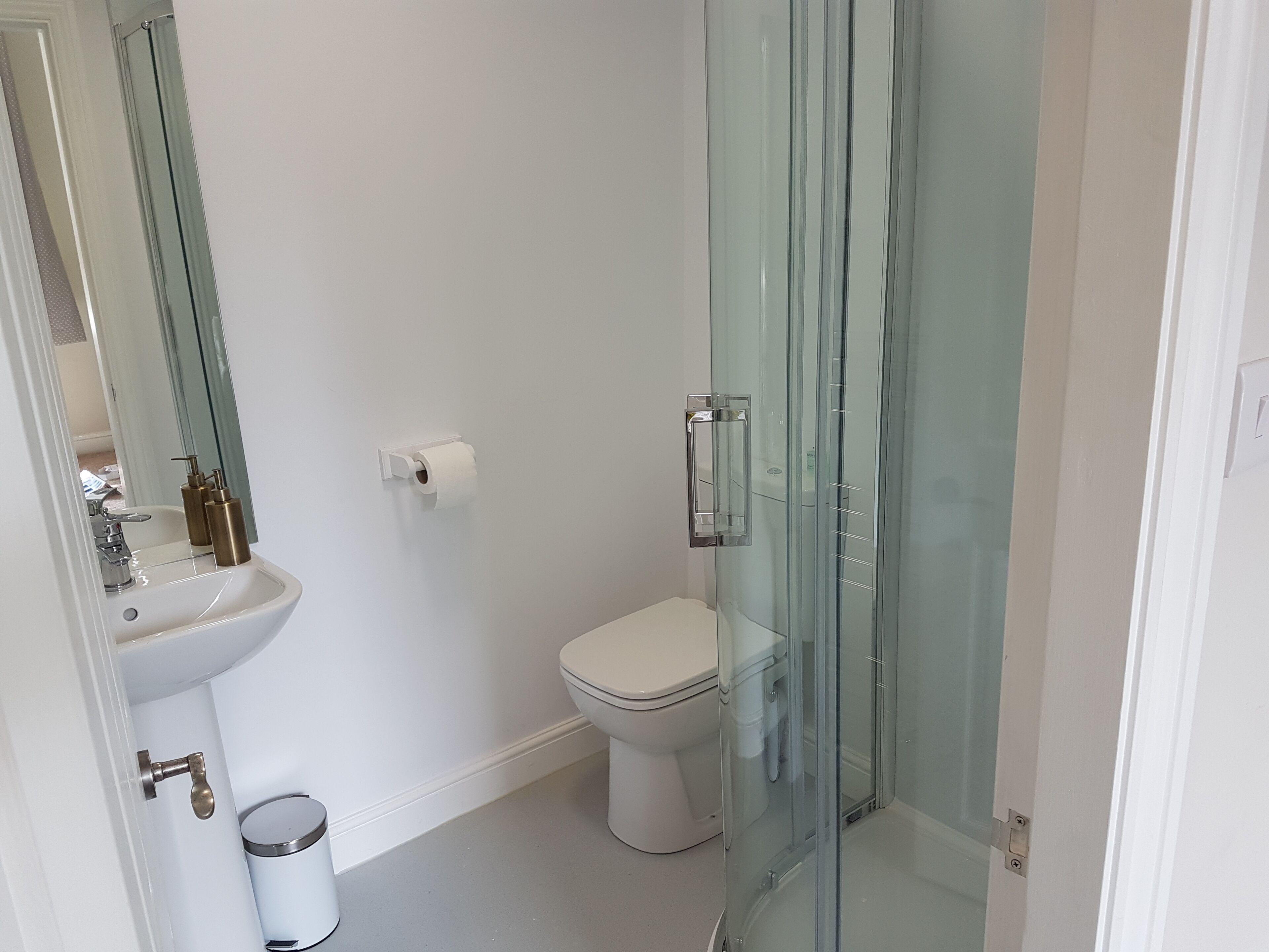Une salle de bain avec une douche à parois de verre, un lavabo blanc et des toilettes.