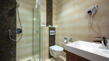 Un baño moderno con ducha envuelta en vidrio, inodoro y lavabo con espejo.