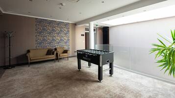 A modern indoor space with a foosball table, a sofa, and a patterned wall.