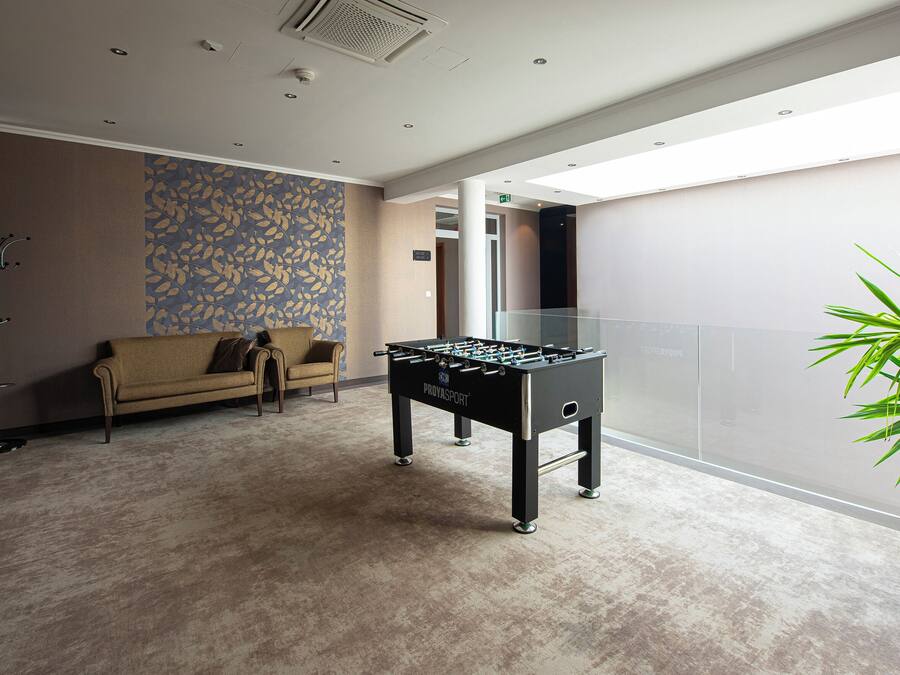 A modern indoor space with a foosball table, a sofa, and a patterned wall.