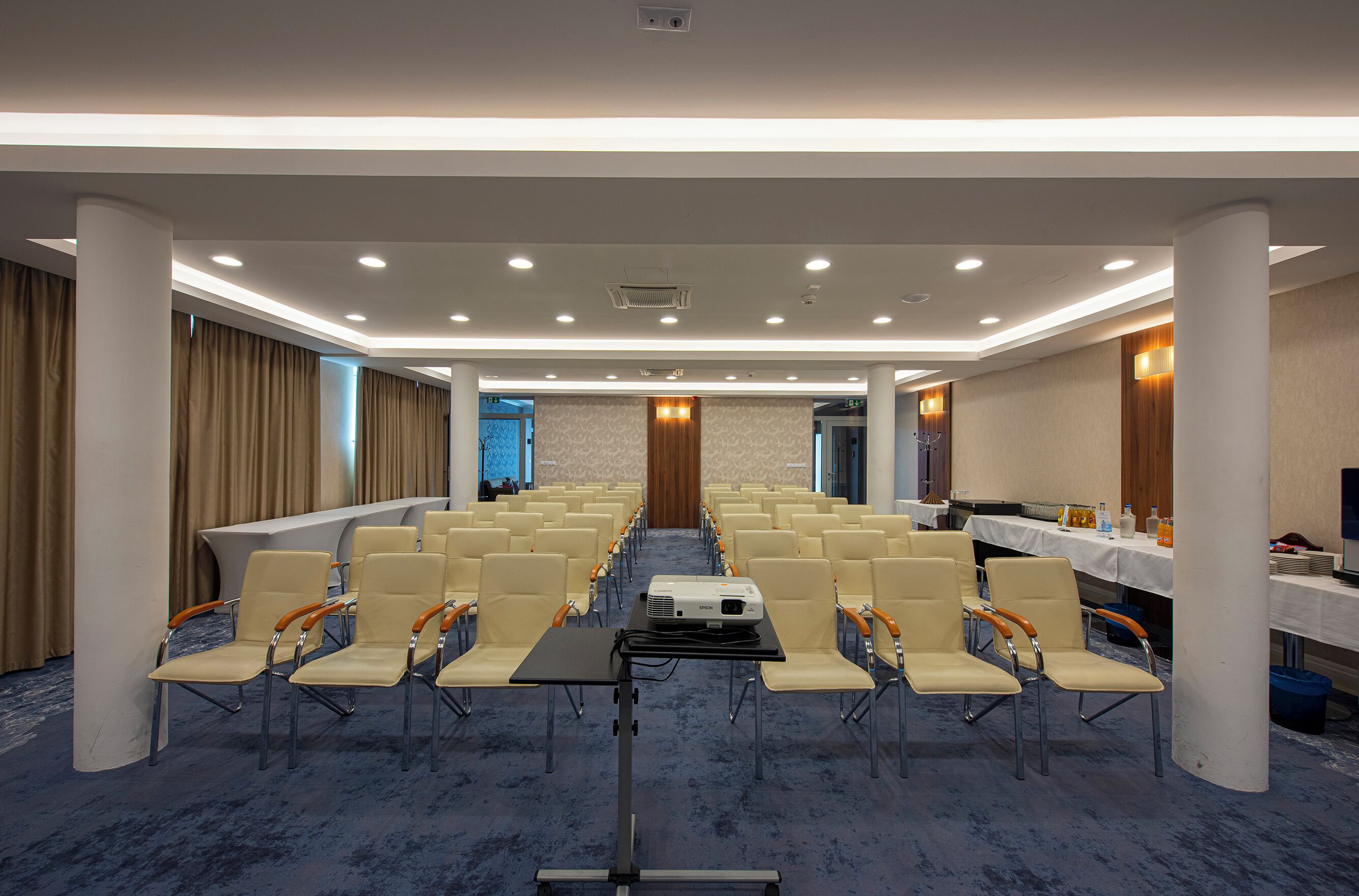 A conference room with rows of chairs, a projector, and tables with amenities.