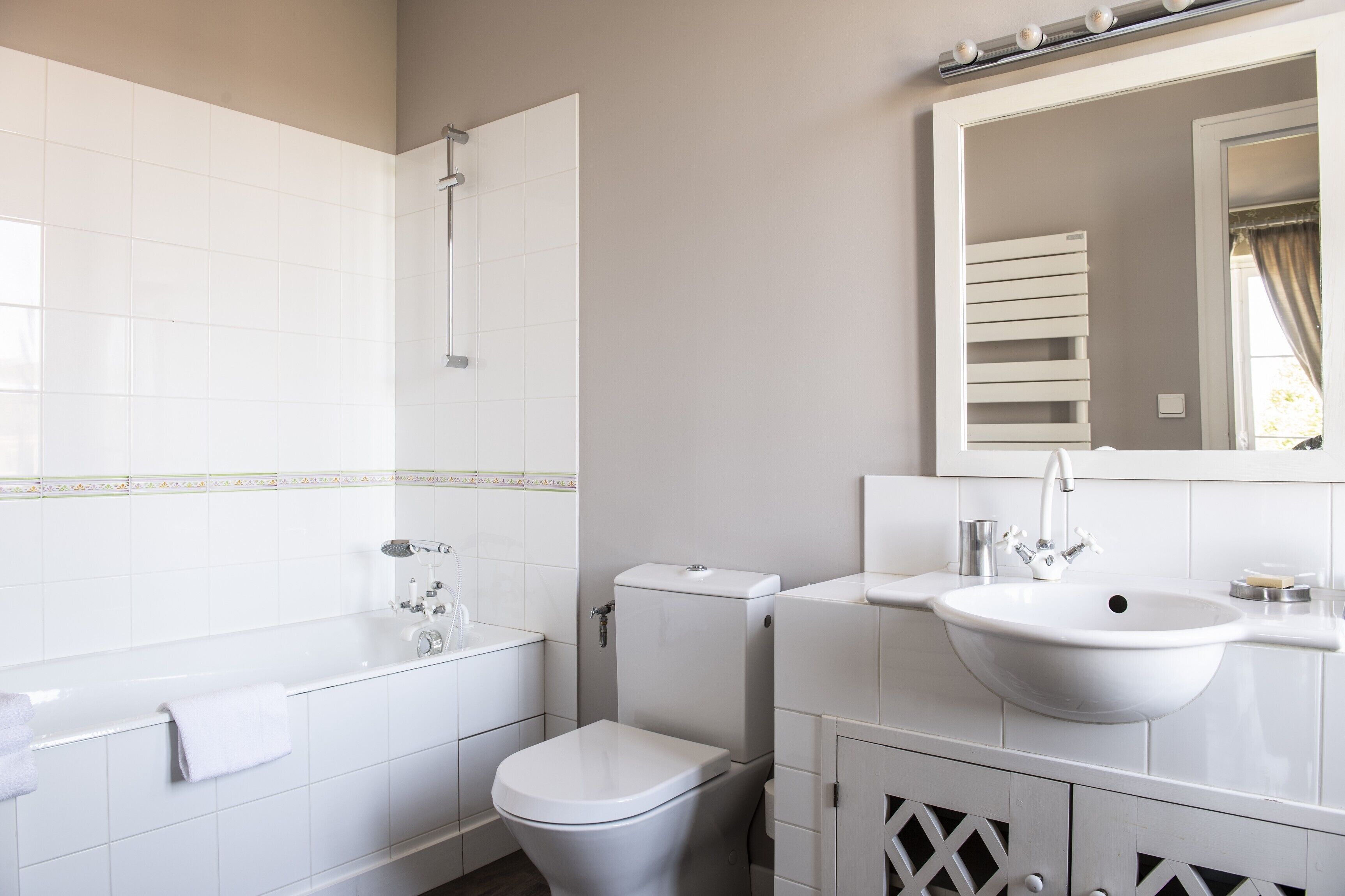 Un baño moderno con bañera, inodoro, lavabo y espejo.