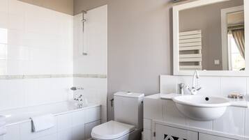 Un baño moderno con bañera, inodoro, lavabo y espejo.
