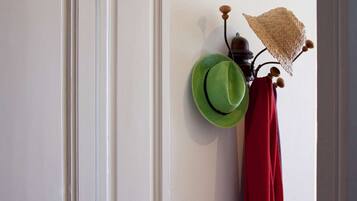 Un perchero de pared con un sombrero verde y una prenda roja.