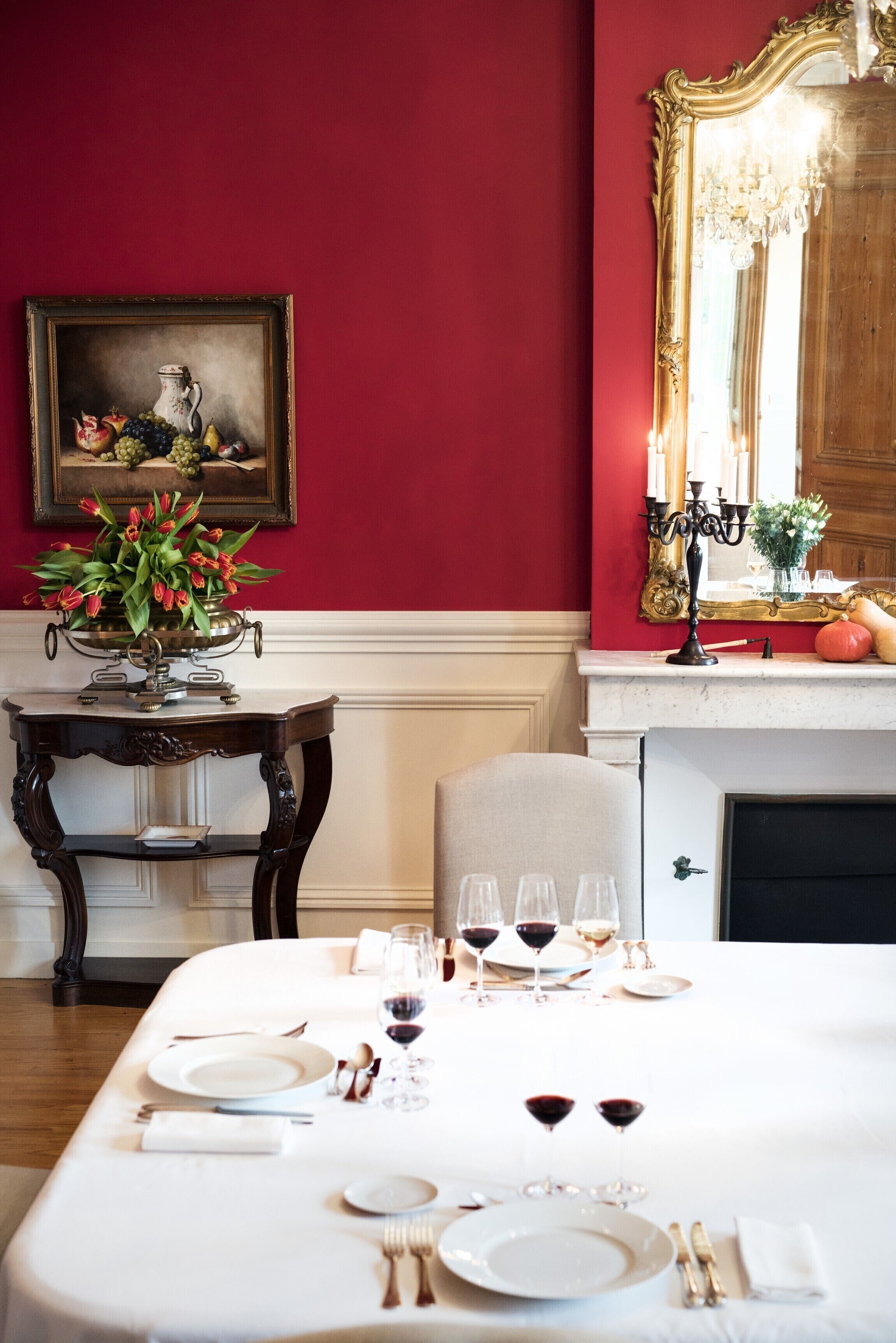 Un comedor con una mesa dispuesta para cuatro, un florero y un cuadro en la pared.