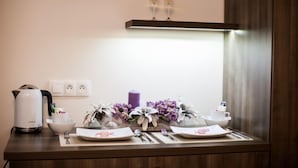 A neatly arranged breakfast table with a kettle, a vase of flowers, and a candle. - Penzion Olomouc (Olomouc)