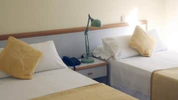 Een hotelkamer met twee eenpersoonsbedden, elk met een kussen en een nachtkastje.