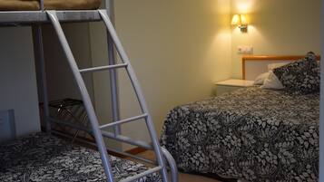 A bunk bed with a ladder, a bedside table with a lamp, and a floral-patterned bedspread.