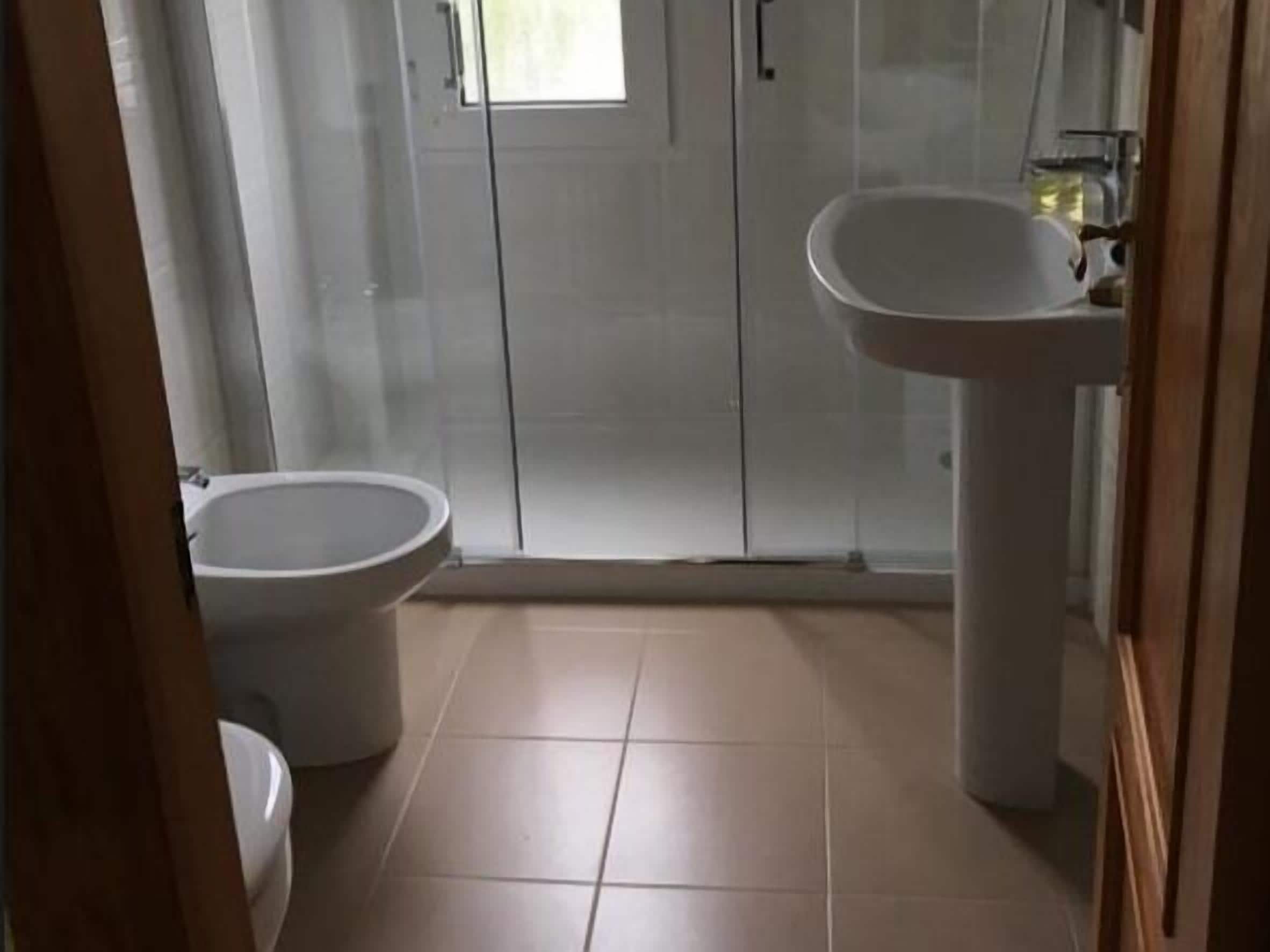 A bathroom with a toilet, a sink, and a glass shower enclosure.