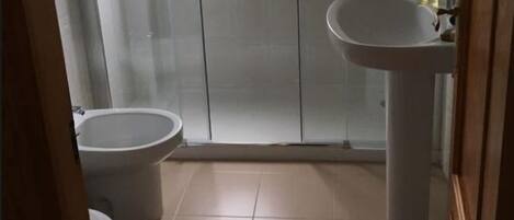 A bathroom with a toilet, a sink, and a glass shower enclosure.