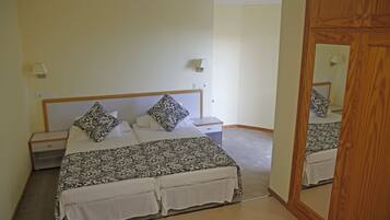 A bedroom with a bed, nightstands, a mirror, and a wall-mounted lamp.