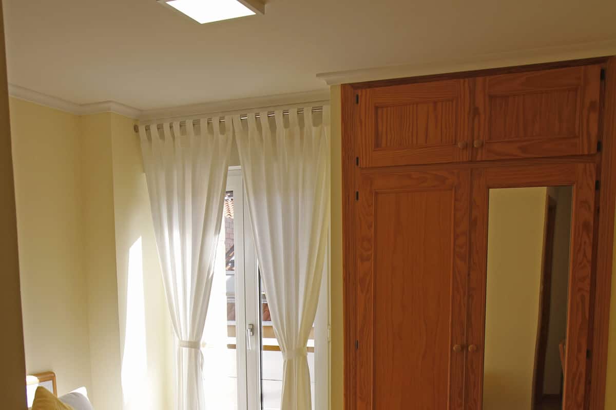 Une chambre d’hôtel avec deux lits, une armoire en bois, un miroir et une petite table.