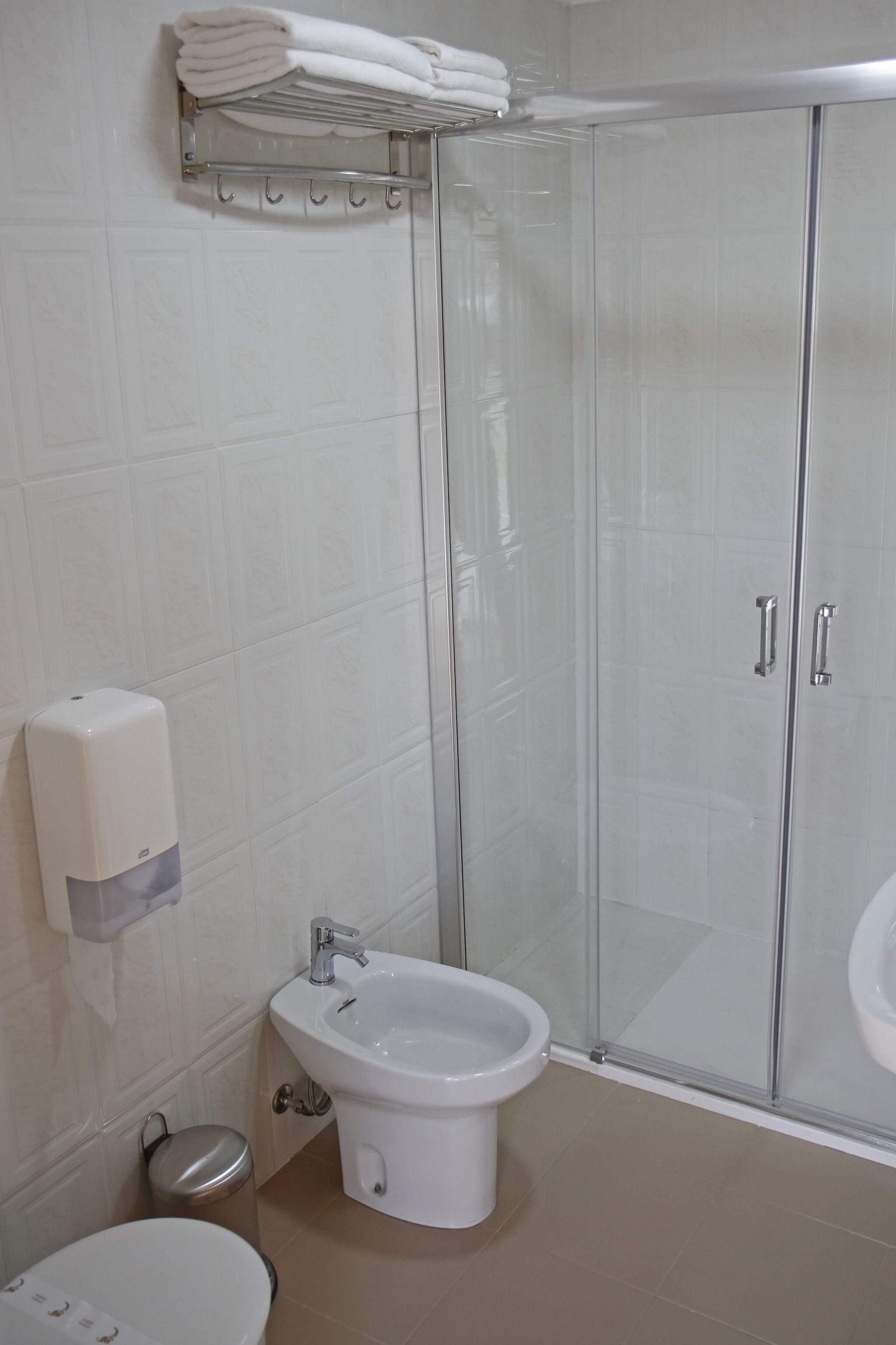 Een badkamer met een douchecabine van glas, een wit wastafelmeubel en een toilet.