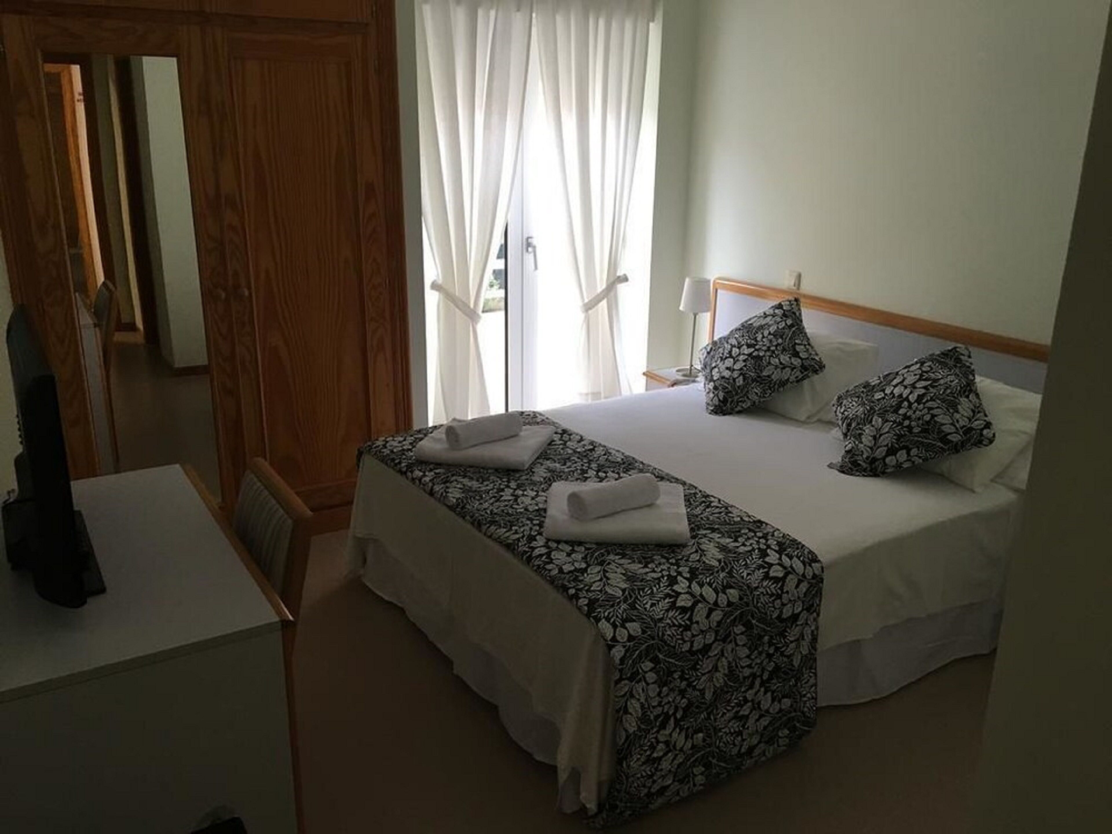 Un dormitorio con cama, escritorio y armario.