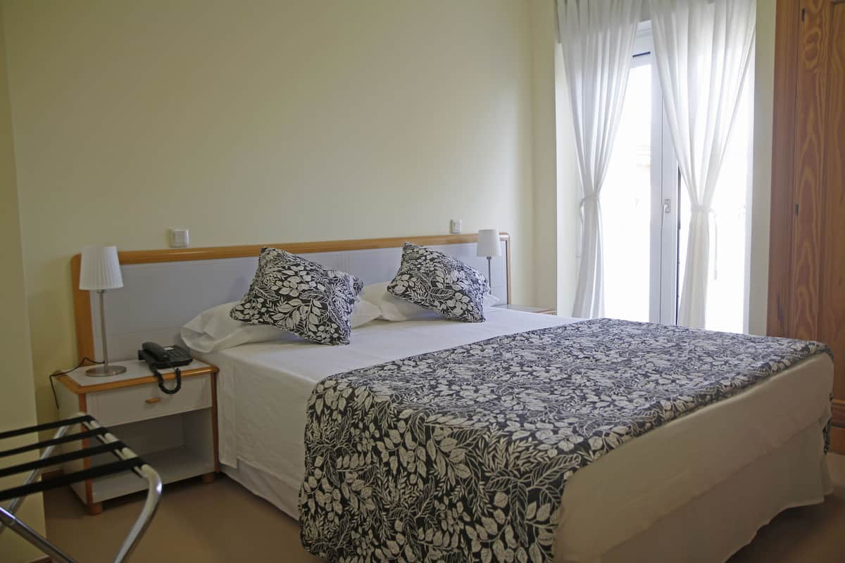 Une chambre à coucher avec un lit, une table de chevet avec un téléphone et une lampe.