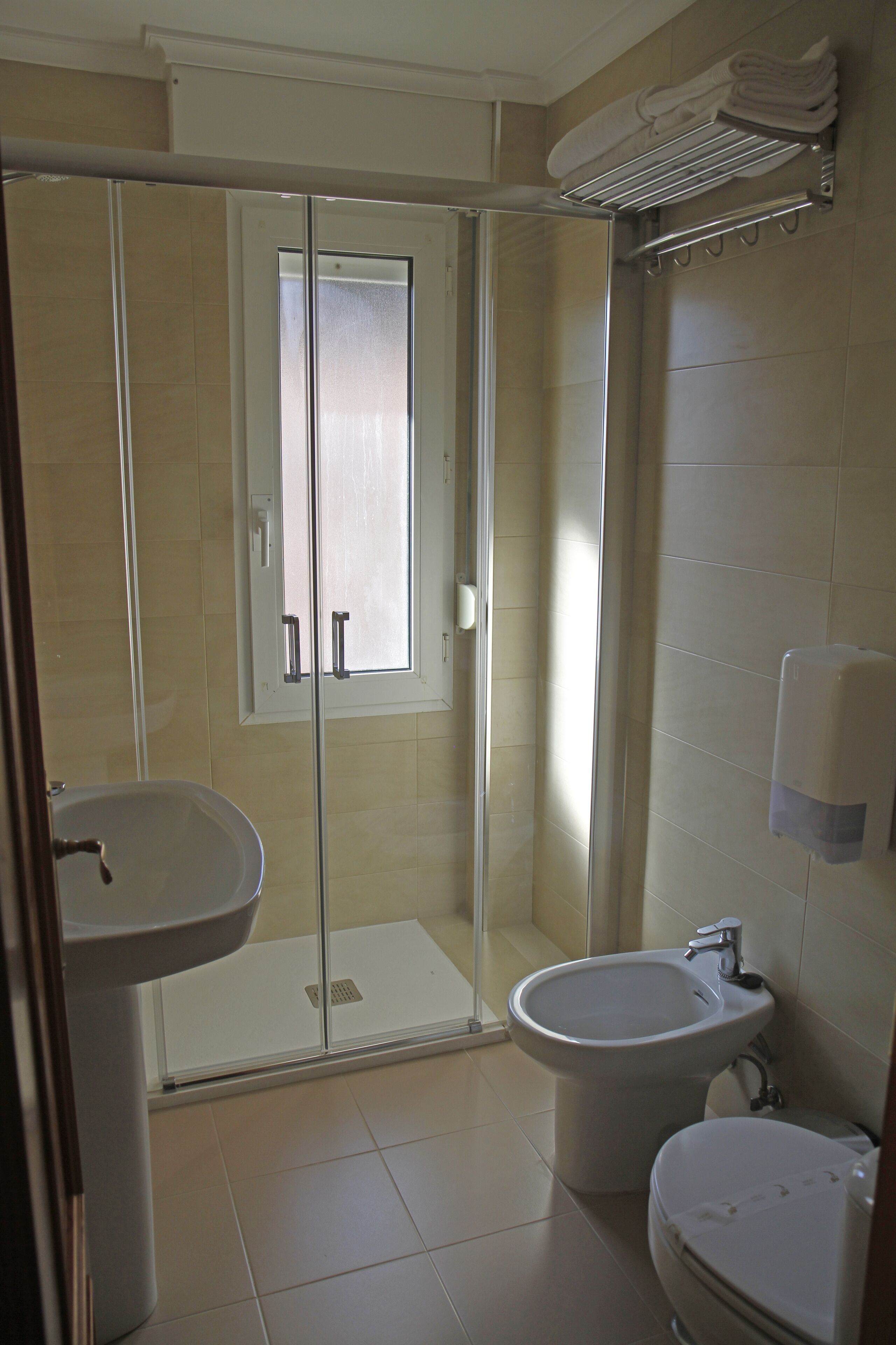 Un baño con ducha de vidrio, lavamanos, un bidé y un inodoro.