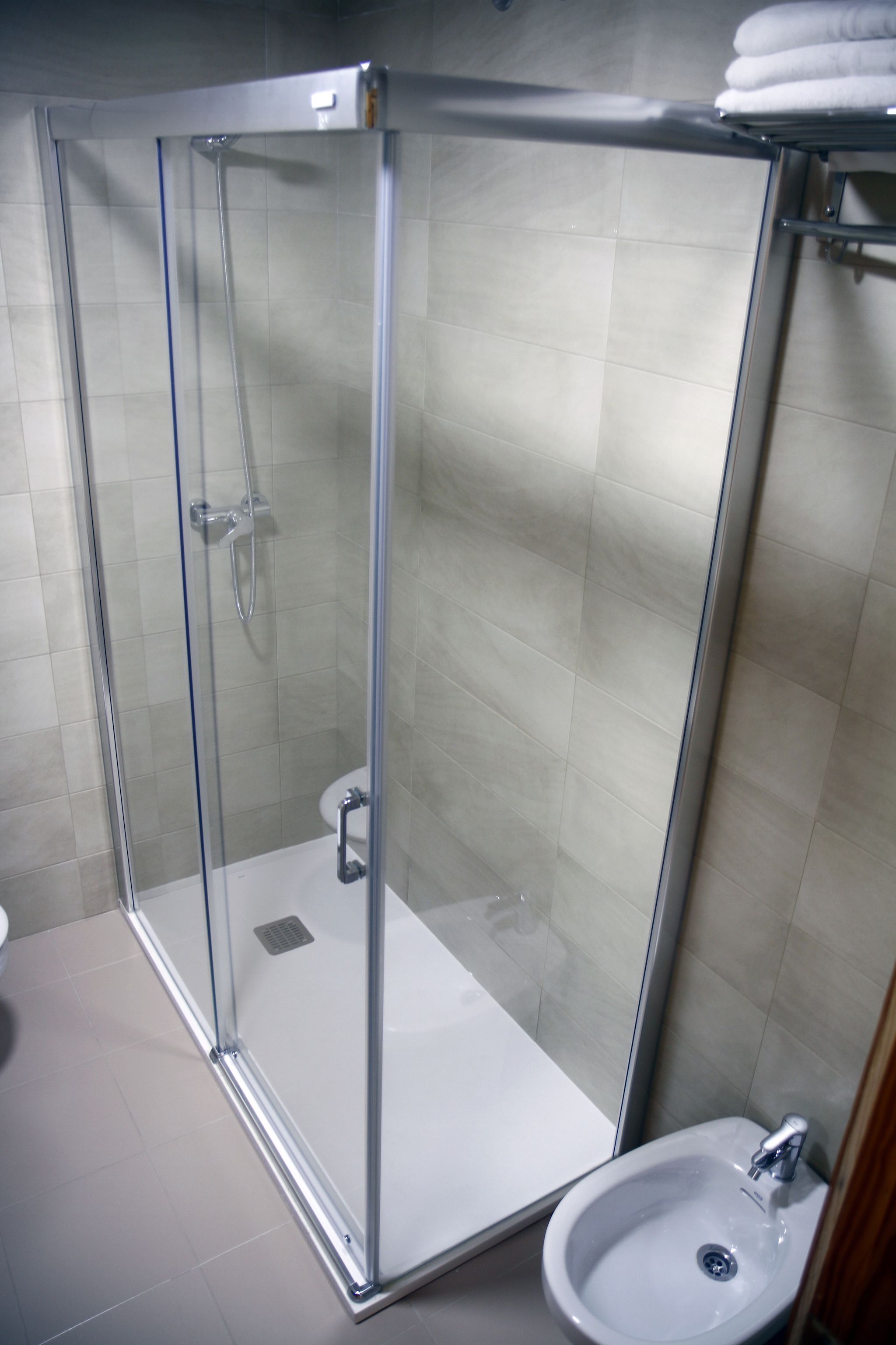 A glass-enclosed shower with a white sink and a toilet.