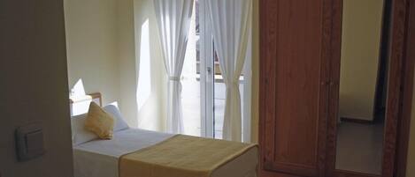 A room with two beds, a wooden wardrobe, and a small table.