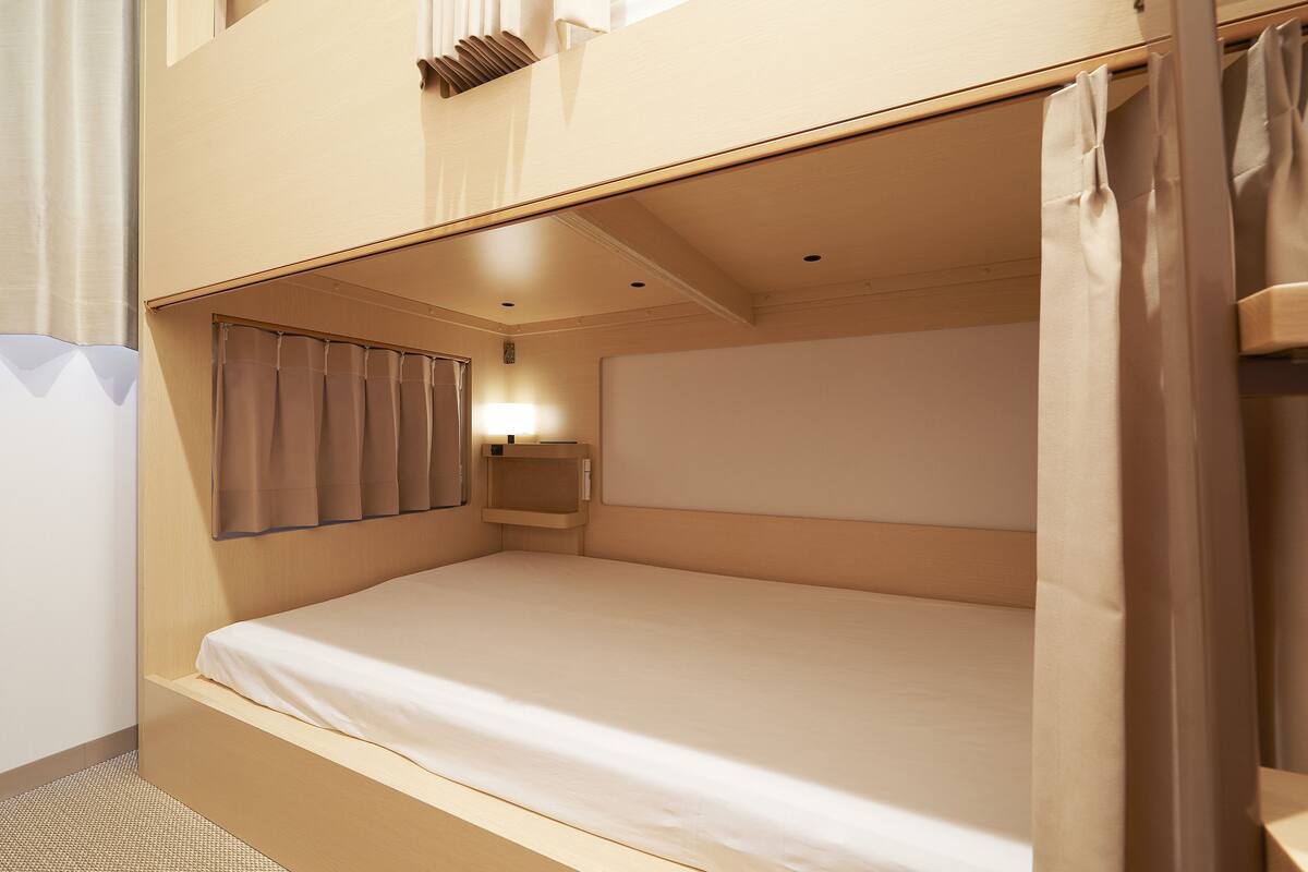 A bunk bed with a headboard, a bedside table, and a wall-mounted shelf.