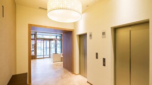 A modern hallway with a wooden bench, a large window, and two elevators.