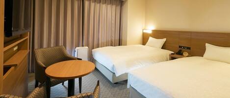 A hotel room with two beds, a TV, a small table, and a chair.