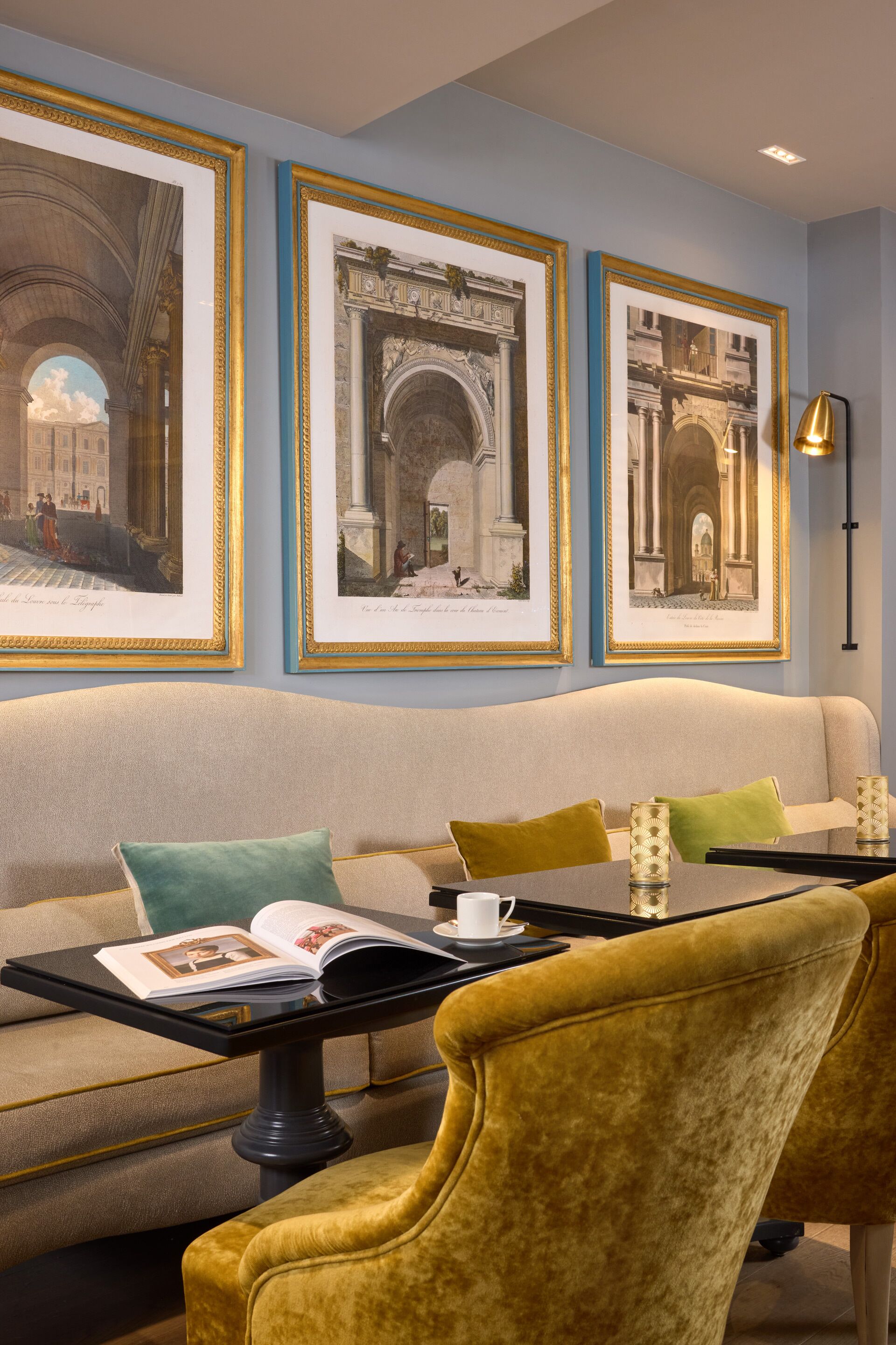 A room with a sofa, armchairs, a coffee table, framed pictures on the wall, and a lamp.