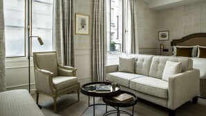 Quarto de hotel com cama, sofá, poltrona e mesinha com bandeja.