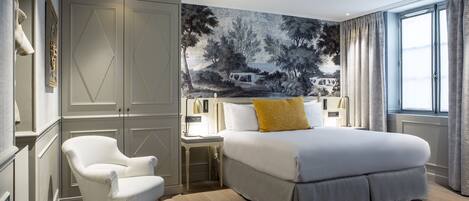 A bedroom with a large bed, a chair, a nightstand, and a wall mural.