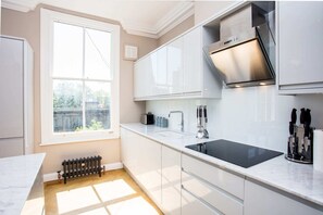 Una cocina moderna con armarios blancos, una estufa negra y un ventanal que aporta luz natural.