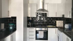 A modern kitchen with black and white tiles, stainless steel appliances, and a central range hood.