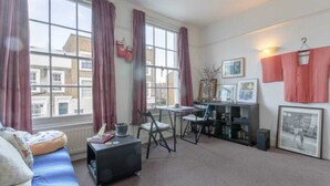 A room with a bed, a desk, a chair, a bookshelf, and a window with curtains.