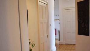 A hallway with wooden flooring, white walls, and doors leading to other rooms. - Traditional Apartment oer the Meadows (Edinburgh)