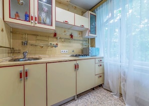 Classic kitchen with cream-colored cabinetry, red accents, and a stainless steel sink.