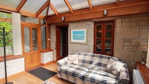 A cozy room with a checkered sofa, a wooden ceiling, stone walls, and a framed picture on the wall. - Auchenheglish Lodges - The Smiddy (Alexandria)